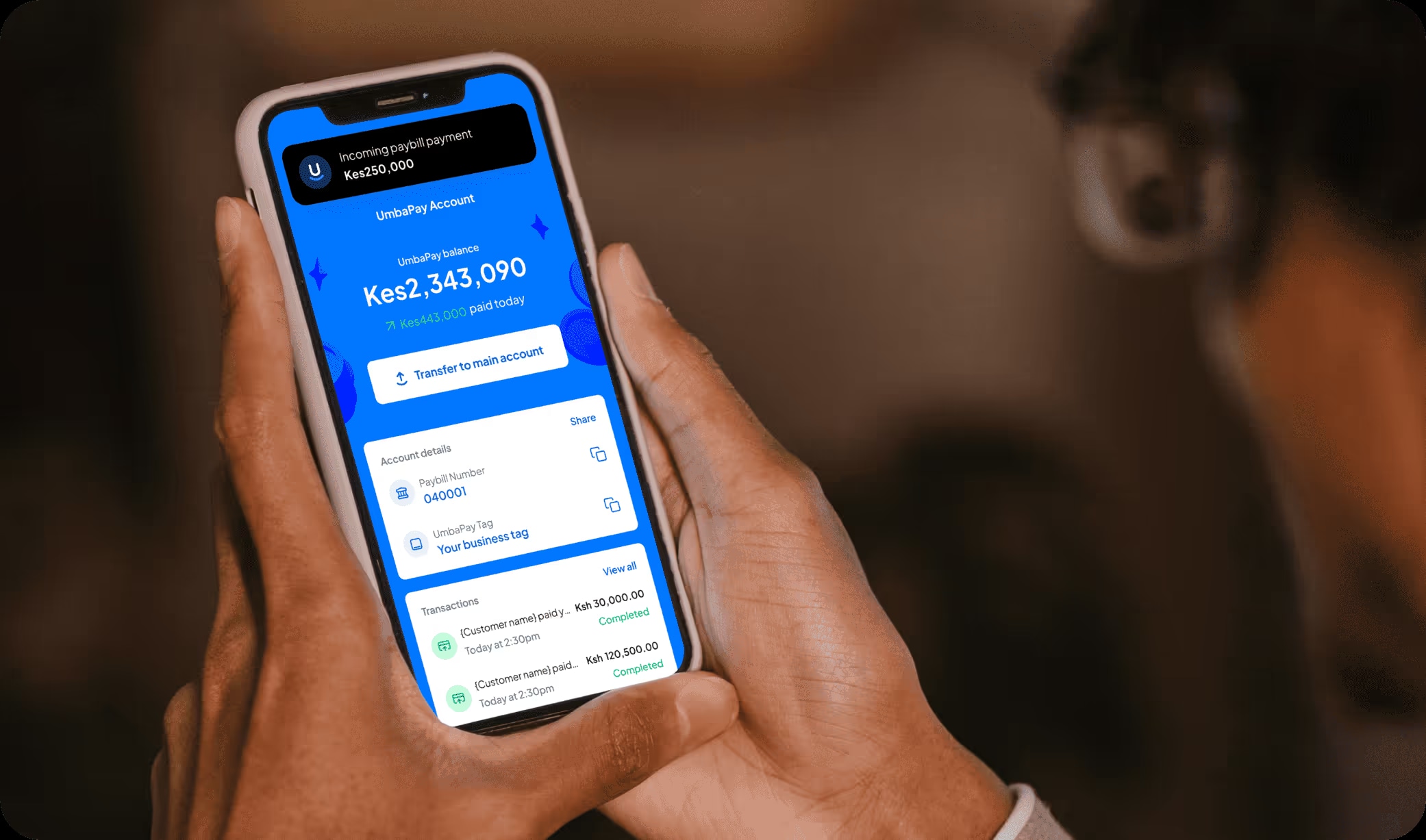 A man holding a phone with UmbaPay account page